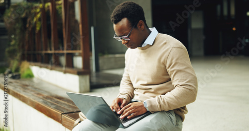 Fotografie Business, black man and typing in city with laptop, research and valuation report for real estate
