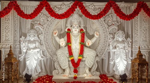 Intricate white sholapith idol display with ornate floral decorations with richly decorated vibrant red floral garlands elaborate beautifully adorned traditional