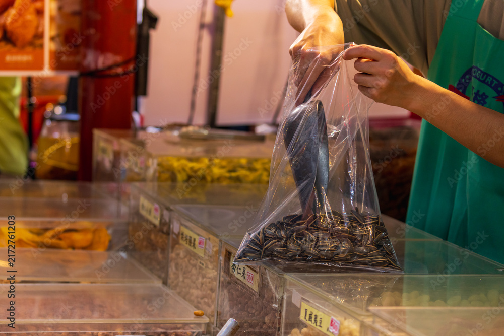 Obraz premium Vendor Bags Sunflower Seeds at Dihua Street Market