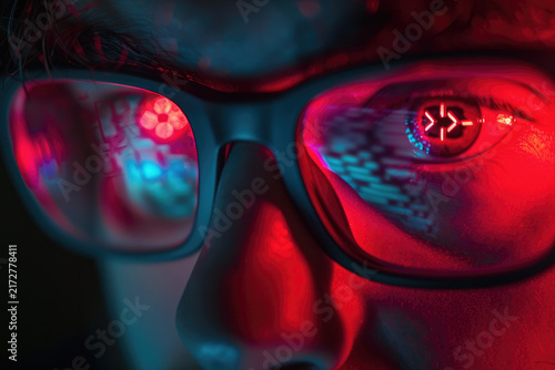 Close Up Face of Hacker Wearing Glasses Reflecting Red Terminal Code and Target Symbol
