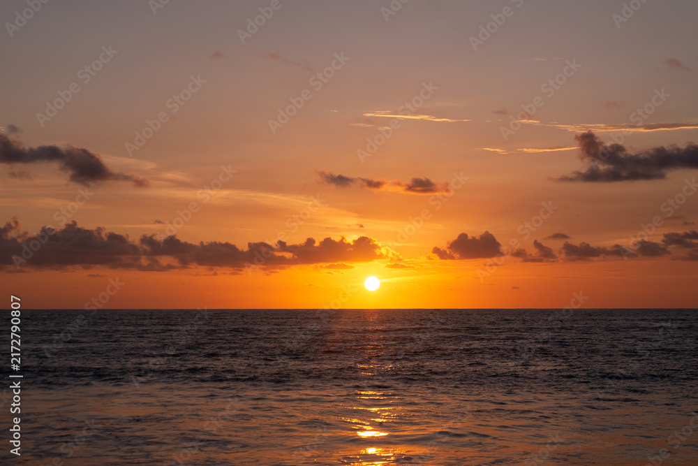 Fototapeta premium Bright sun disk setting over ocean horizon with golden reflection on calm sea water