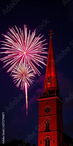 Fireworks beside illuminated church tower at night