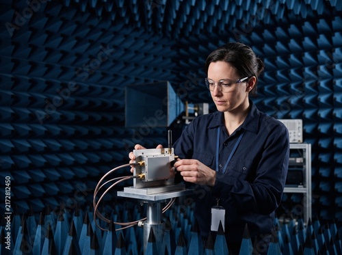 RF Engineer adjusting satellite communication transceiver in anechoic chamber