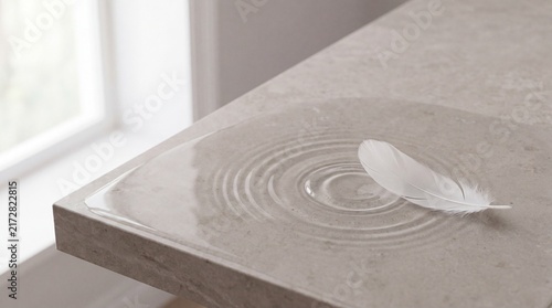 White feather resting on water ripples over stone surface