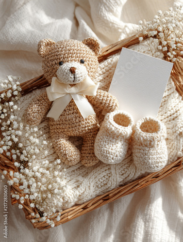 Crocheted teddy bear with bow and baby booties in wicker basket with knitted blanket and dried flowers, soft warm tones evoke comfort and care