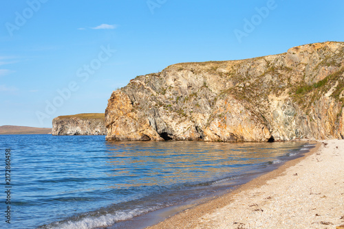 Baikal Lake in summer. View of rocky shore of Olkhon Island and sandy beach of shallow bay of Small Sea on sunny day in August. Beautiful seascape. Summer travels. Natural seaside background