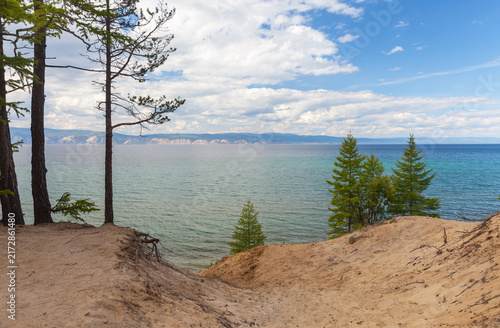 Baikal Lake in summer. Sandy shore of Olkhon Island. Scenic landscape with green larch trees on the sand beach of the Small Sea on a sunny August day. Nature Park. Travels and outdoor recreation