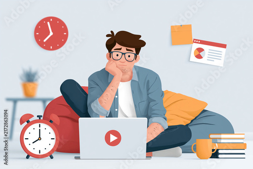 Young man sits cross-legged, thoughtful, on a beanbag. He gazes at his laptop, hand resting on chin. Clocks, books, and sticky notes surround him. Study, work, or learning moments feel captured here
