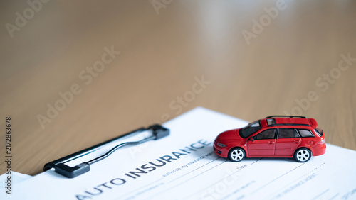 Fotografie Close-up of red model car on auto insurance document and clipboard, representing vehicle insurance, policy, risk and protection with copy space