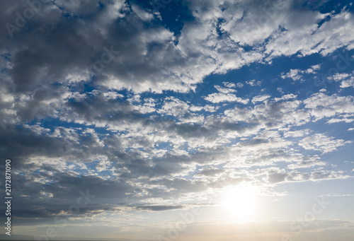 Sunlight pierces through scattered clouds on vast blue sky