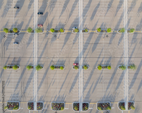 Overhead drone shot shows organized parking area with few vehicles and shrubs