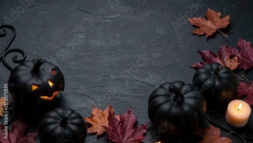 moody halloween flat lay of black carved pumpkins and autumn leaves on dark slate for seasonal marketing