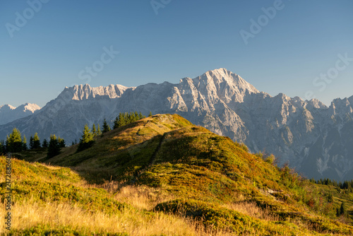 Majestic alpine mountain peaks illuminated by warm golden sunrise light, creating a breathtaking summer landscape in the Austrian Alps, perfect for travel, tourism and premium nature imagery.
