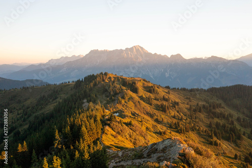 Majestic alpine mountain peaks illuminated by warm golden sunrise light, creating a breathtaking summer landscape in the Austrian Alps, perfect for travel, tourism and premium nature imagery.
