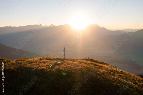 Majestic alpine mountain peaks illuminated by warm golden sunrise light, creating a breathtaking summer landscape in the Austrian Alps, perfect for travel, tourism and premium nature imagery.