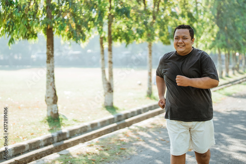 portrait of an overweight man jogging in the park in the morning with copyspace