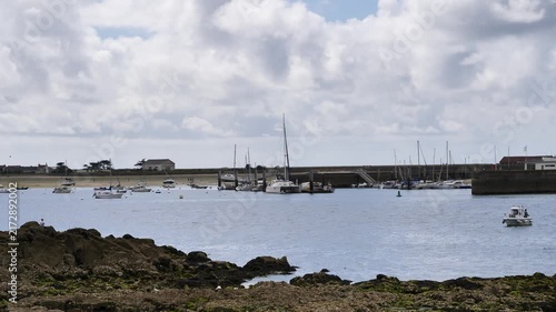 Small marina with sailboats and motorboats at low tide under a cloudy sky.