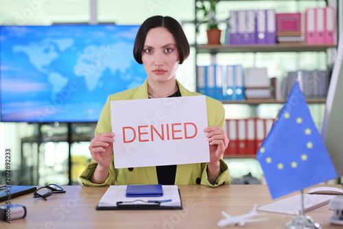 Female clerk displays Denied word for visa decision in European consular office. Worker presents rejection notice confirming refused application