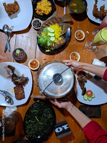 Foto Overhead flat lay of an Indonesian traditional food feast served on a rustic woo
