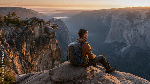 Man on Mountain Peak A lone hiker sits on a rocky summit, gazing out at a breathtaking vista of a vast mountain range bathed in the golden hues of sunrise.