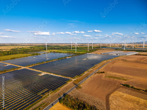 Quadro su tela Solar panels and wind turbines in a rural landscape during clear weather