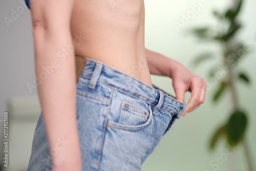 Quadro su tela Woman pulling down her oversized jeans on her stomach closeup