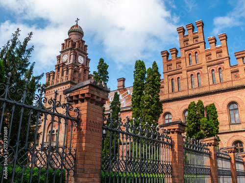 Chernivtsi, Ukraine shows a historic building with clock tower and trees under a clear blue sky