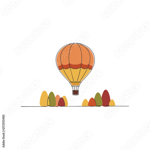 Hot air balloon floating over autumn landscape with trees