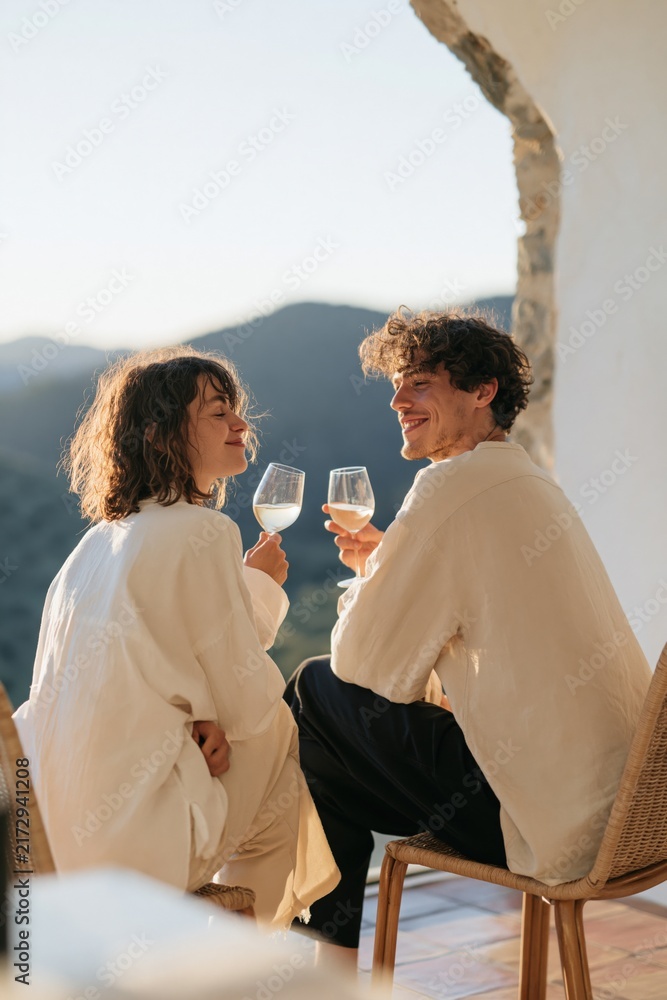 Naklejka premium Romantic sunset terrace scene with couple toasting wine glasses for lifestyle background and cozy travel banner design