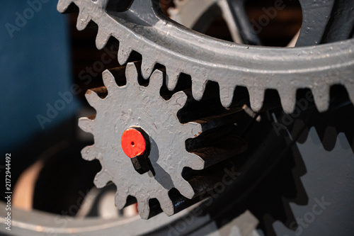Close-up of old heavy industrial spur gears meshing together, showing a pinion gear engaged with a large ring gear made of cast iron.