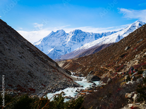 Cuadro en lienzo Snow-capped mountain peaks towering over a winding river valley and rocky slopes