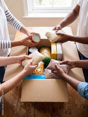 Food drive volunteers packing box cans rice pasta donation charity a diverse group fills a cardboard box with canned goods rice pasta for food drive promotion and community nutrition campaigns