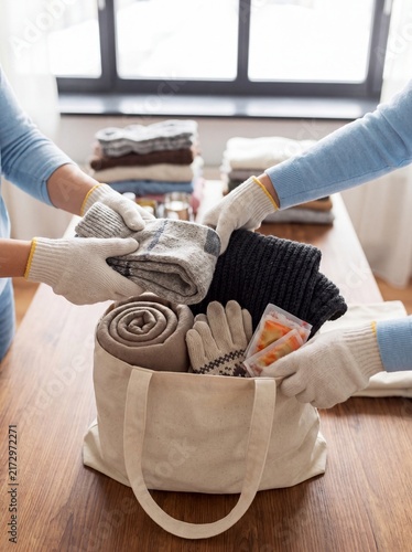 Winter clothing donation volunteers packing blankets gloves scarves community support hands fill a reusable bag with warm blankets scarves for winter relief campaigns and clothing donation outreach