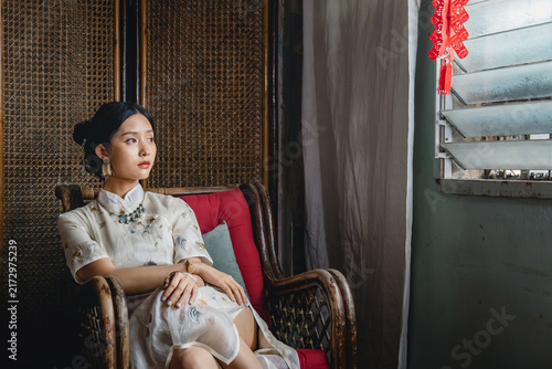 Photography Lonely Asian woman daydreaming and gazing sideways from rattan armchair near old