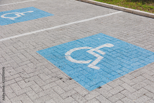 Accessible parking spaces marked with blue wheelchair symbols on a paved parking lot, highlighting disabled parking, accessibility and inclusive infrastructure.