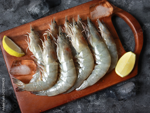 Fresh raw white prawns on wooden cutting board. Sustainable food.