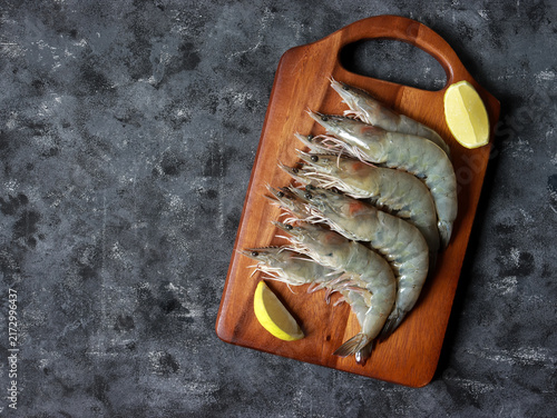 Fresh raw white prawns on wooden cutting board. Sustainable food.
