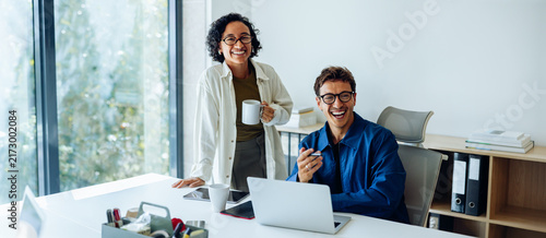 Two coworkers smile during casual office chat