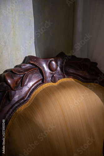 Photography Close-up of carved wooden backrest of vintage armchair in soft warm light