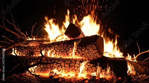 Burning firewood displaying intense heat and light in the dark night