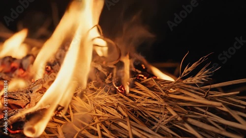 Burning straw fire flames and embers glowing in dark environment