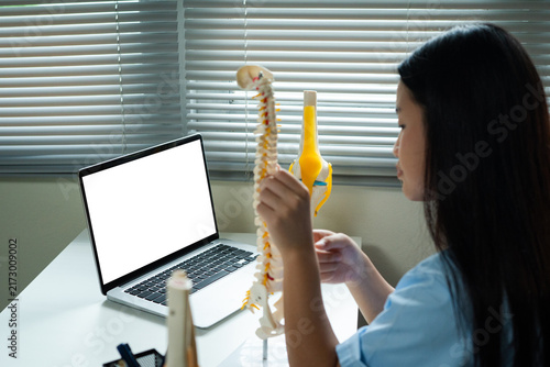 Foto Teenage Student Learning Anatomy Online with Spinal Model and Laptop for Virtual