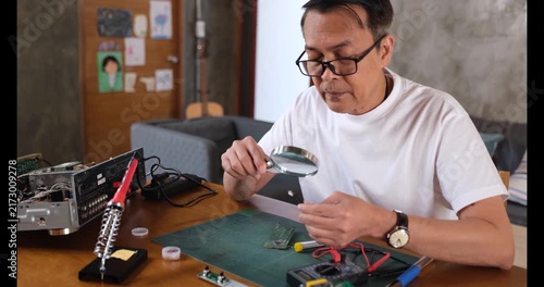 Adult Man Repair Electronics with Magnifying Glass at Workbench, Inspecting Circuit Board and Using Soldering Iron