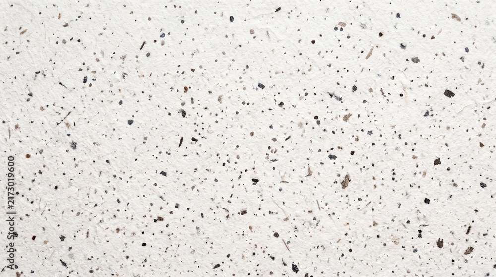 Naklejka premium White speckled paper texture with black grain particles and recycled material surface.