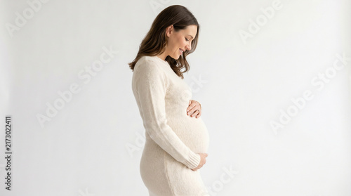 Side Profile of Smiling Pregnant Woman Holding Her Growing Belly