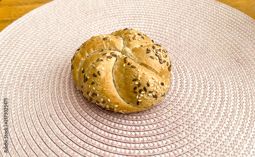 Konstfotografi Seeded Kaiser roll bread multigrain sesame flax bakery bun round crusty breakfast fresh baked on woven placemat at home