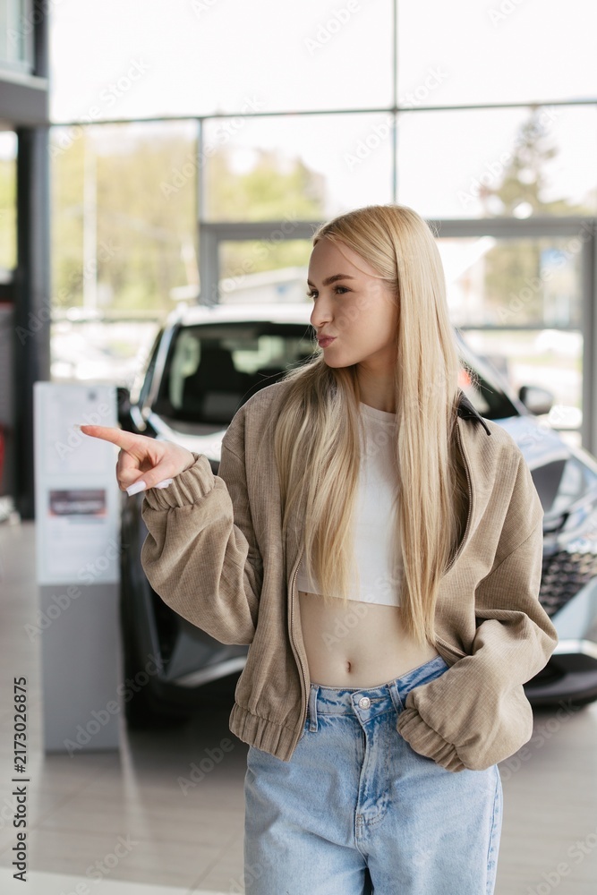 Fototapeta premium Woman pointing finger in car dealership