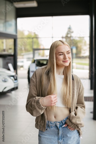 Young woman smiling in modern car dealership