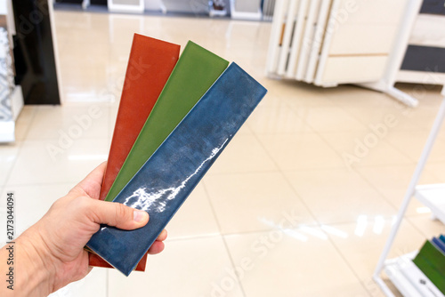 Multicolored ceramic tiles in hand. Selection of ceramic tile color.