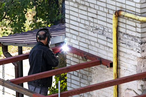 A welder is installing a metal structure on the street.